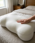 Hand placing Velmesta Cloud Alignment Pillow on bed
