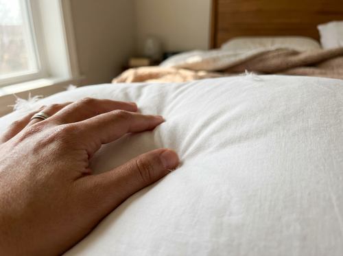 Close-up of a hand pressing into the plush down fill of the Velmesta Cloud Down Pillow